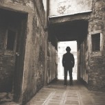 A photo of someone playing as Jack the Ripper outside an old building.