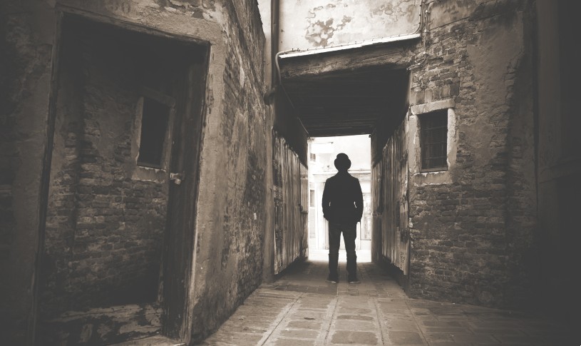 A photo of someone playing as Jack the Ripper outside an old building.